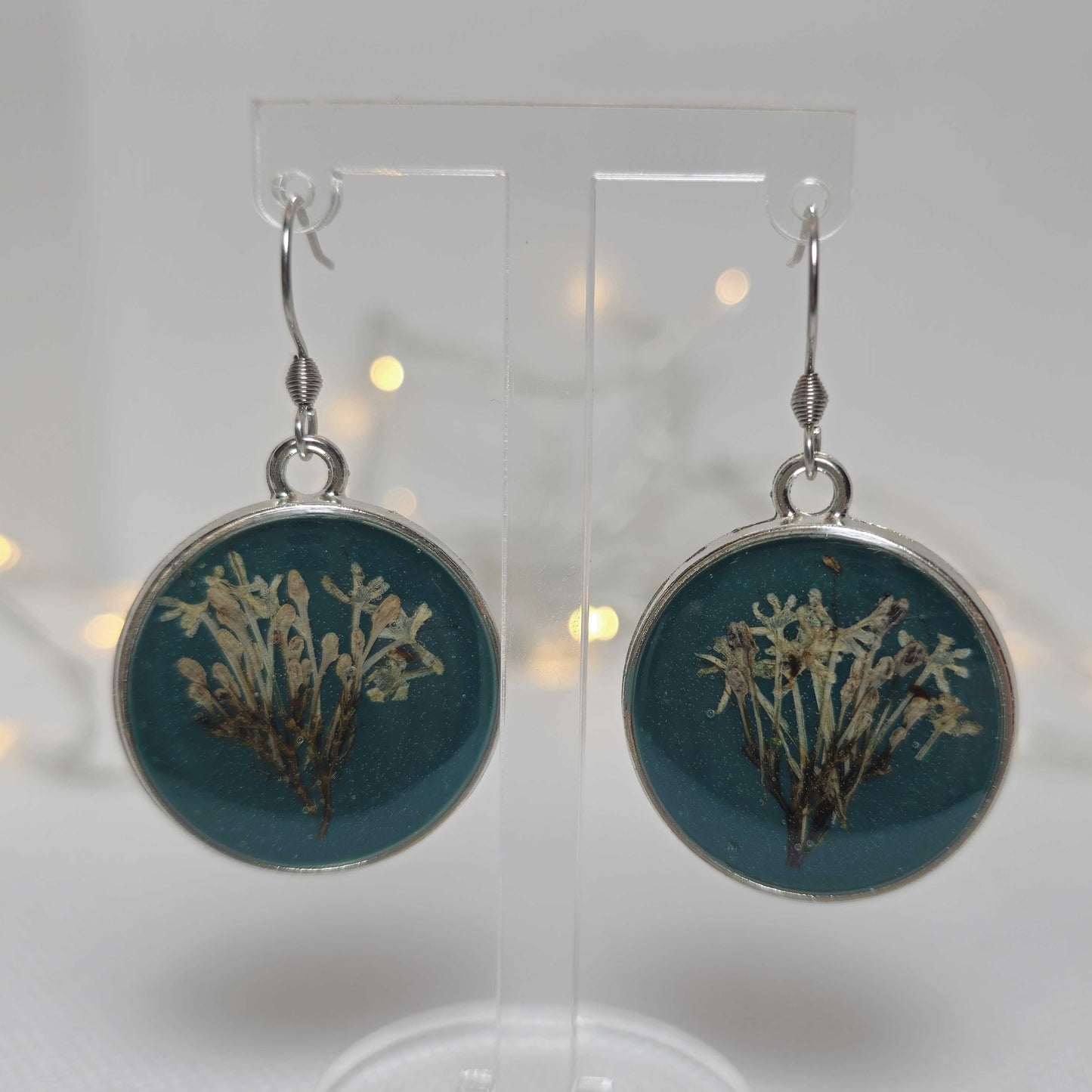 Earrings - Acrylic resin. Navy blue with white flowers framed in a round silver-look bezel.