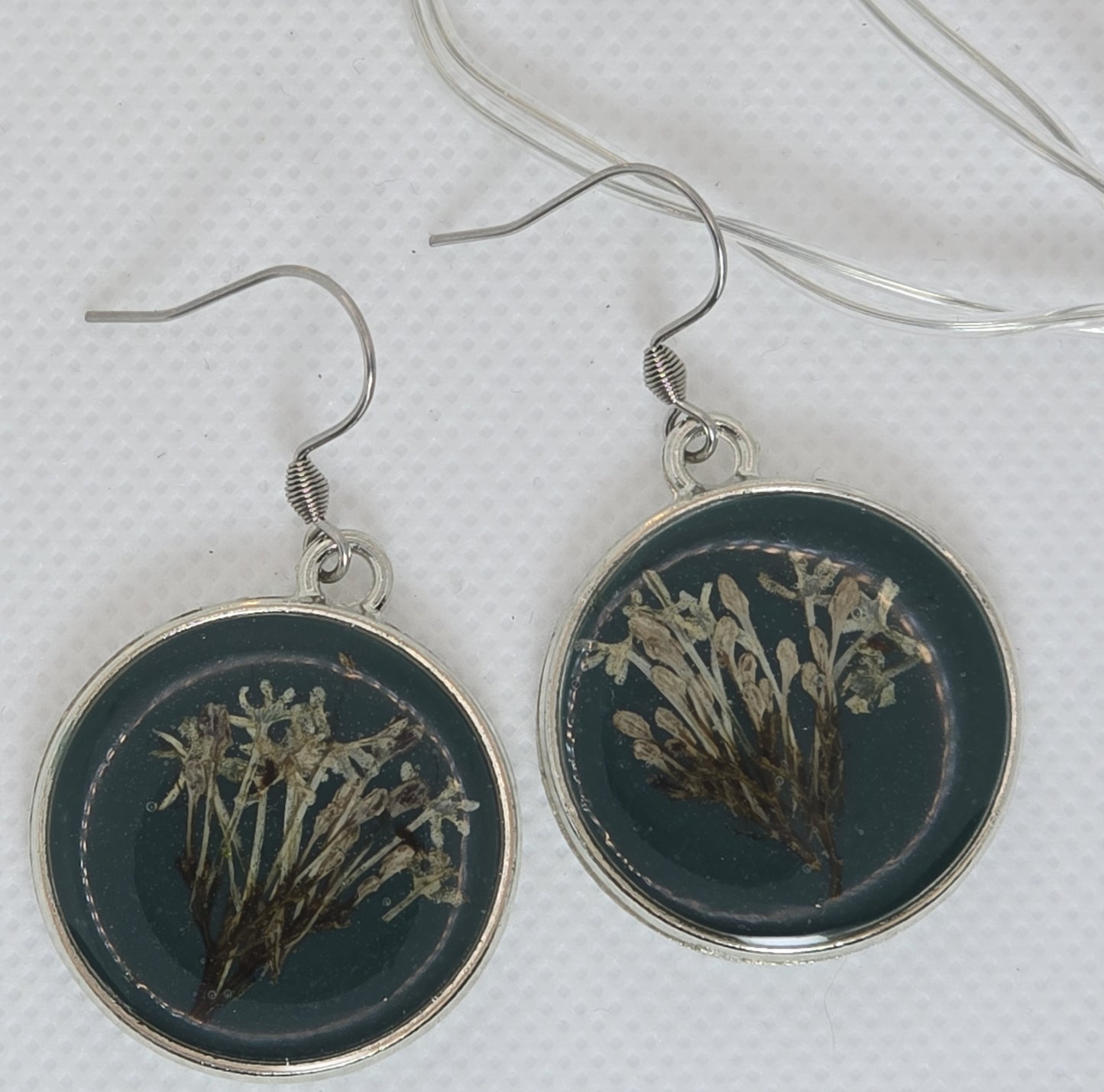 Earrings - Acrylic resin. Navy blue with white flowers framed in a round silver-look bezel.