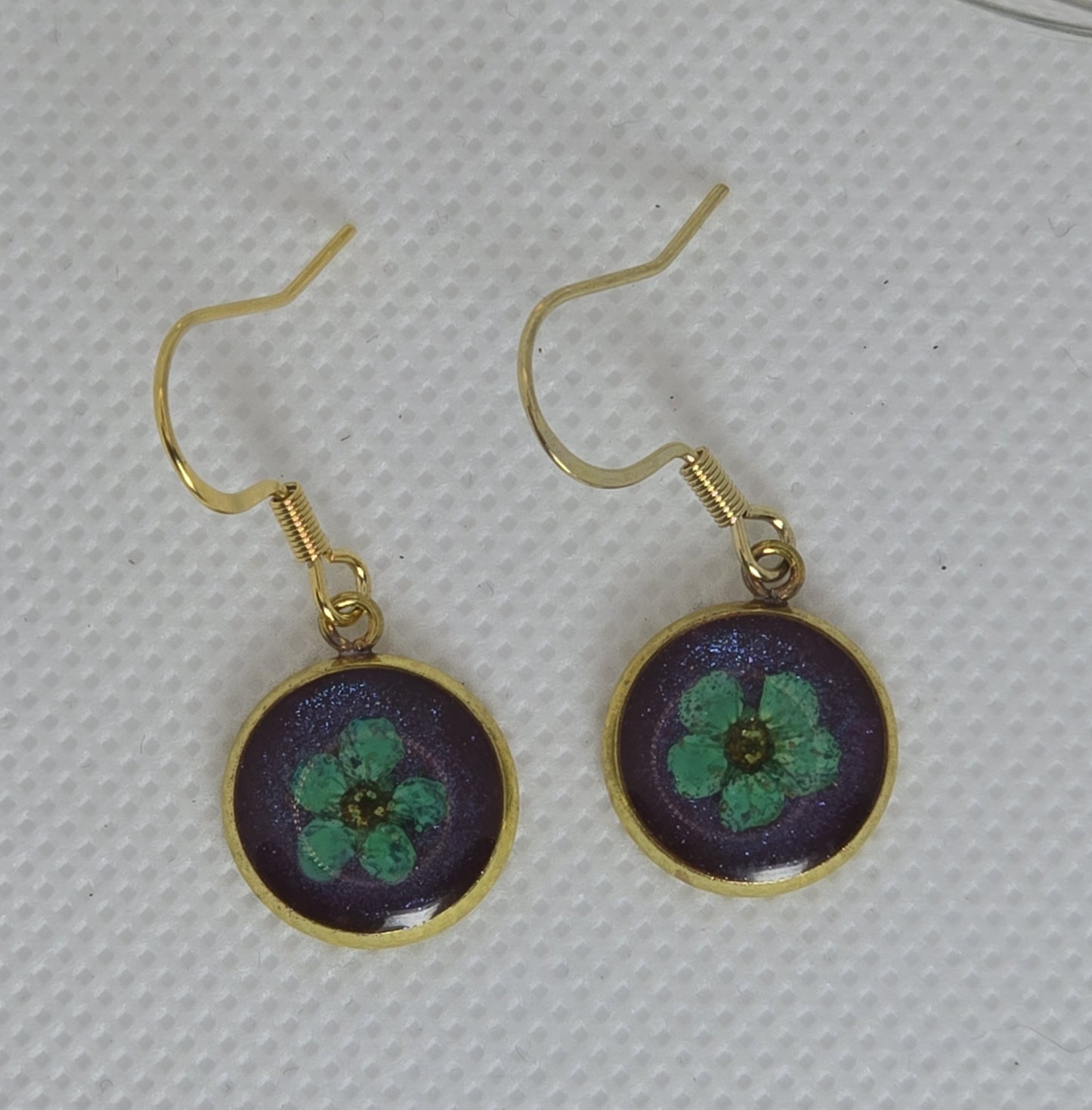 Earrings - Acrylic resin, single light blue flower resting on a bed of shimmering deep blue resin,