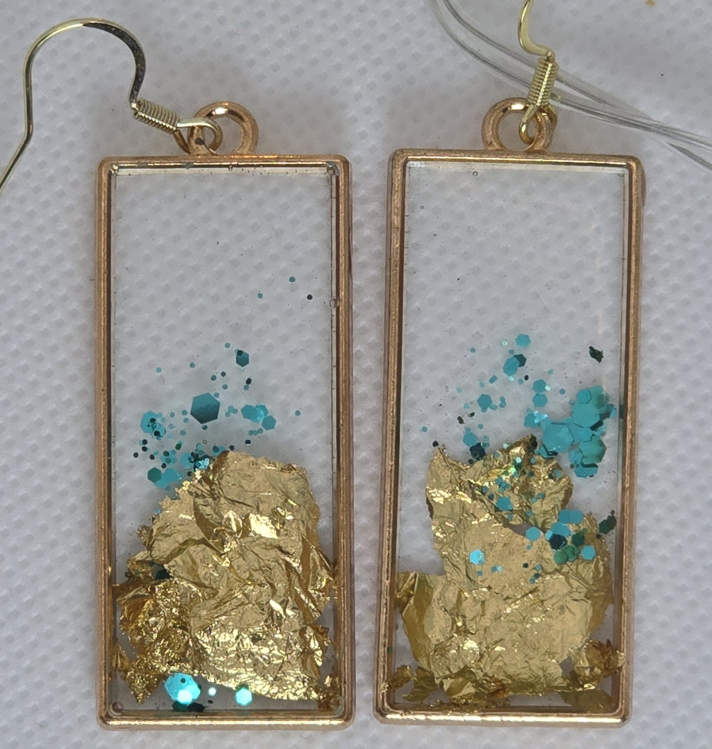 Earrings - Acrylic resin encasing gold leaf and turquoise glitter in a gold rectangular frame
