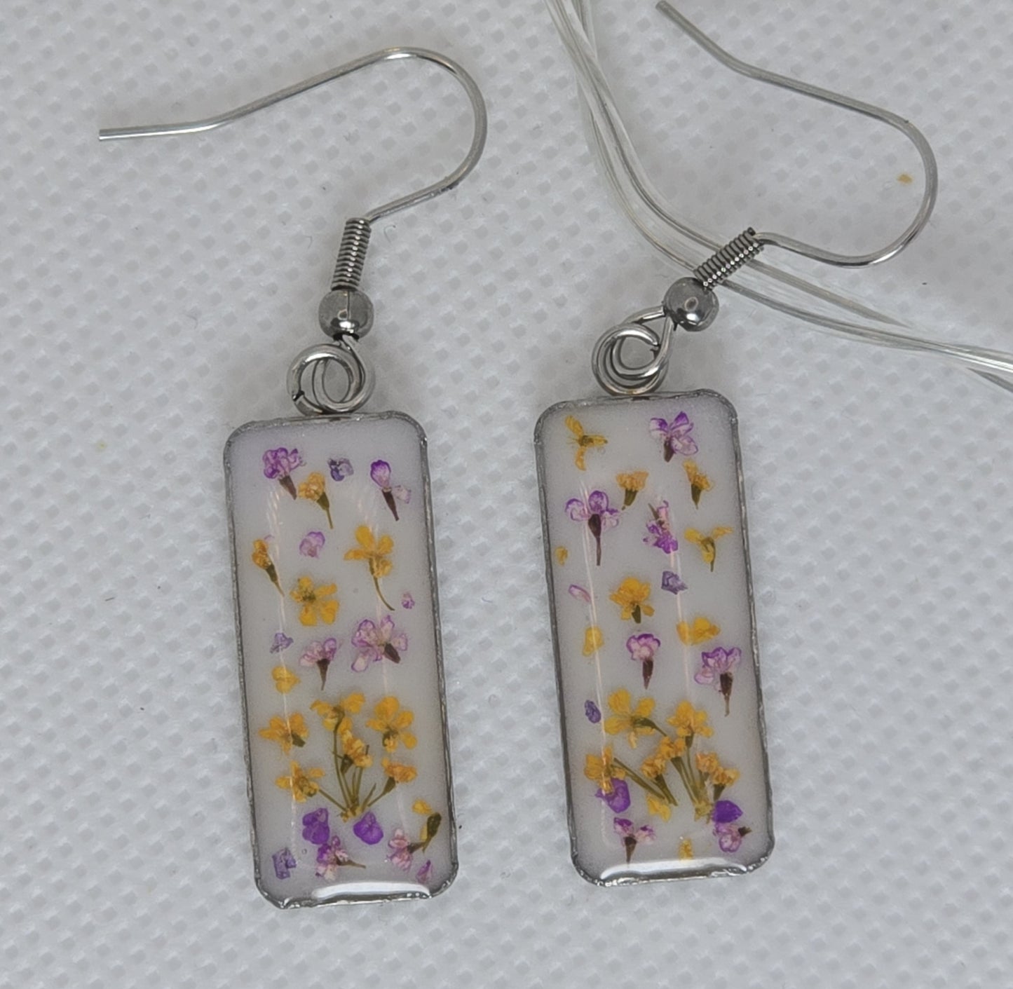 Earrings - resin-filled rectangular tray filled a sprinkling of delicate Queen Anne's lace flowers in orange and purple, on a bed of white