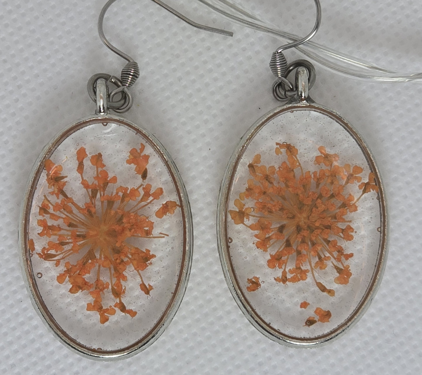 Earrings: Oval shaped bezel with orange Queen Anne's Lace floating in clear resin