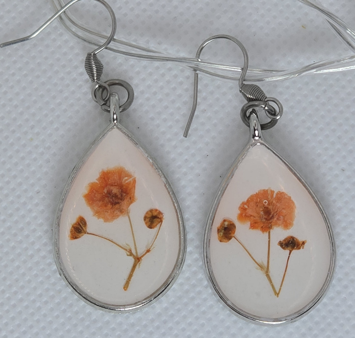Earring- teardrop shaped earring with orange gyposophilia flower on a base of white acrylic resin