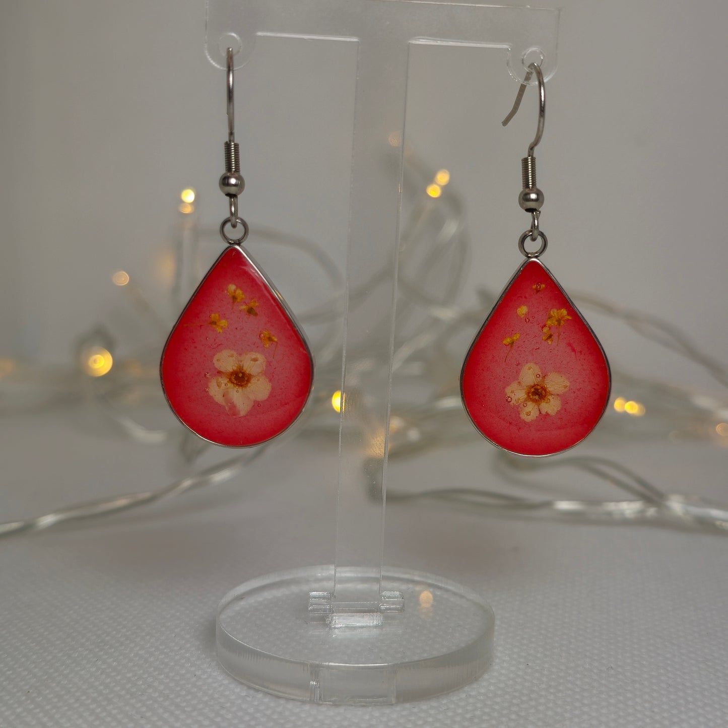 Earrings: silver-look teardrop shaped earrings with a white Alyssum flower and tiny Queen Anne's Lace, floating in translucent red acrylic resin