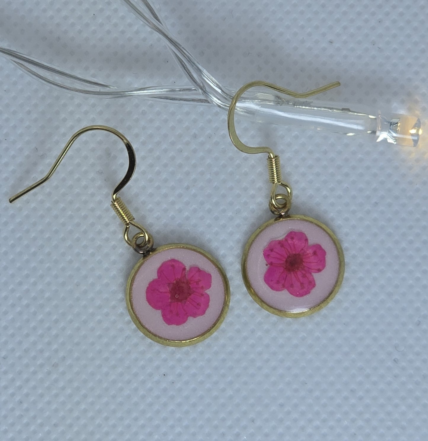 Earrings, Single cerise pink Alyssum flowers resting on beds of pale pink acrylic resin, contained in a dainty round gold-coloured bezel.
