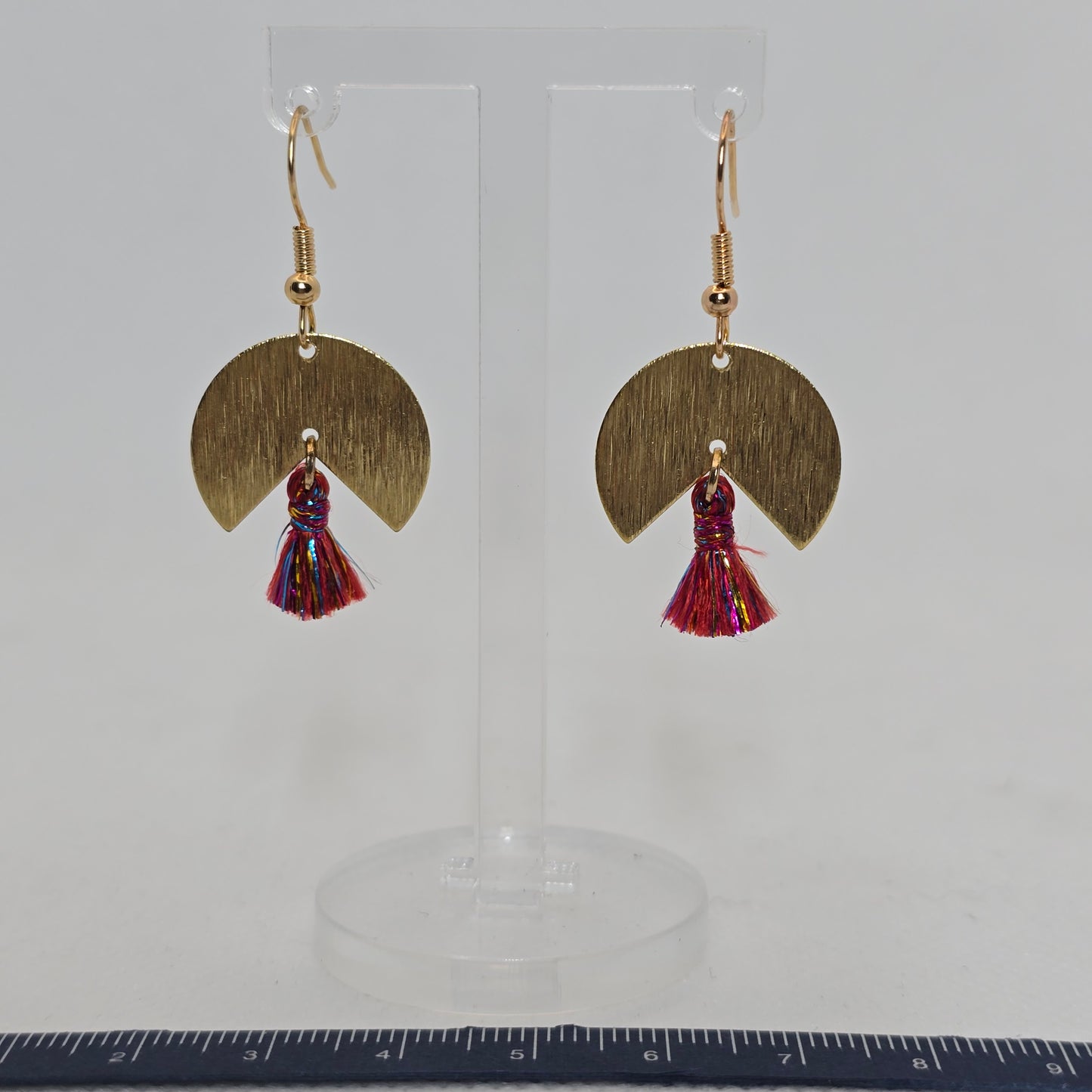 Earring- pie-shaped brushed brass earring with a delicate red and gold tassel dangle