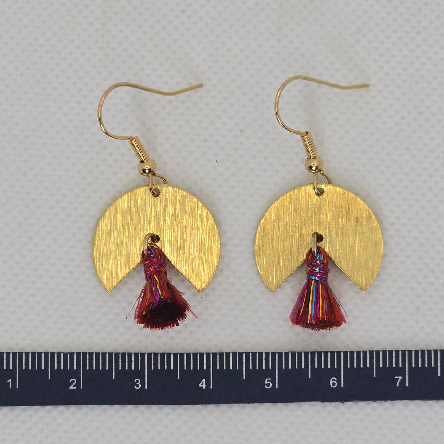 Earring- pie-shaped brushed brass earring with a delicate red and gold tassel dangle