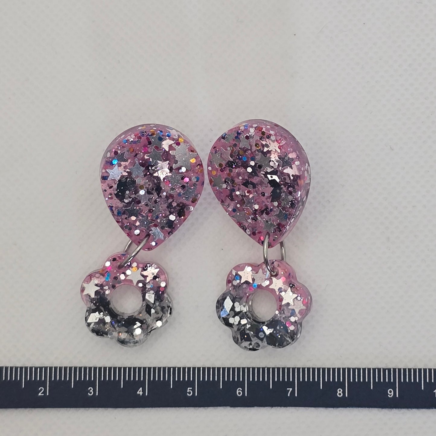 Glitter-filled pink and grey dangly earrings with chunky glitter and silver stars.