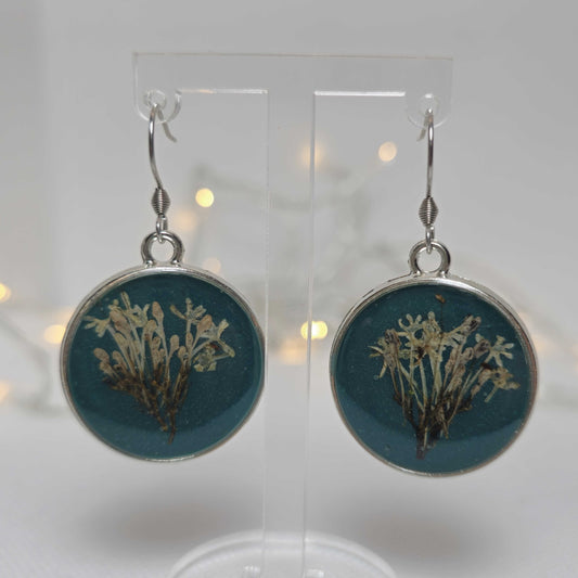 Earrings - Acrylic resin. Navy blue with white flowers framed in a round silver-look bezel.
