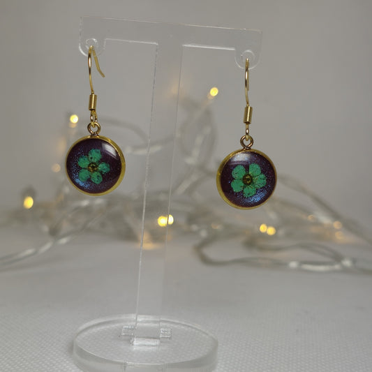 Earrings - Acrylic resin, single light blue flower resting on a bed of shimmering deep blue resin,