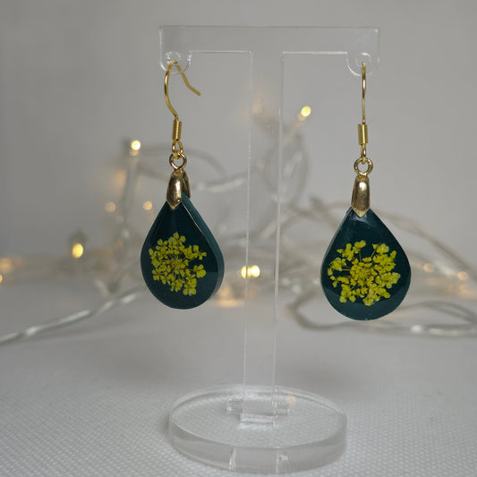 Earrings: deep green acrylic resin earrings in a teardrop shape containing a bouquet of yellow Queen Anne lace flowers,