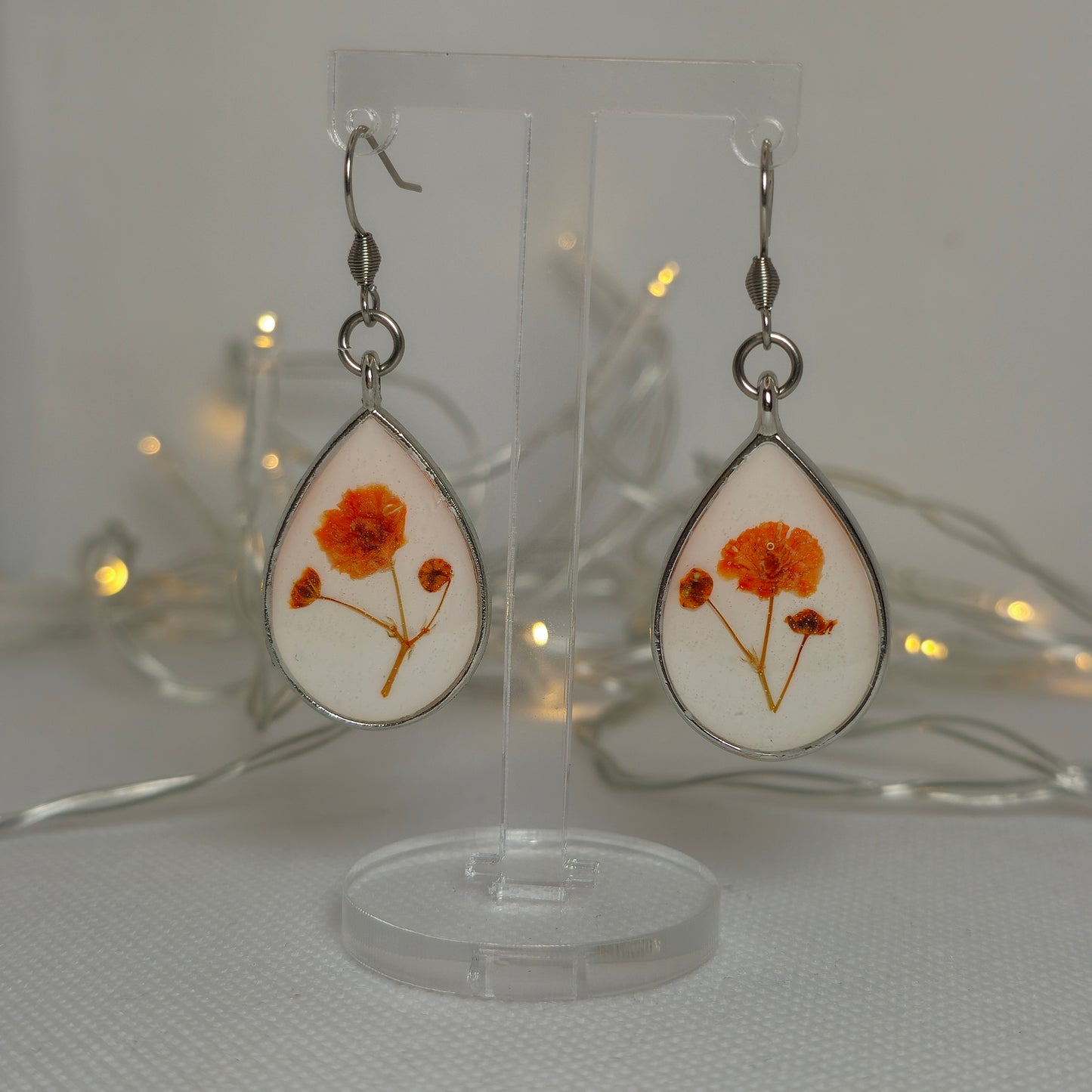 Earring- teardrop shaped earring with orange gyposophilia flower on a base of white acrylic resin