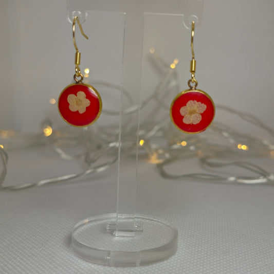Earrings: Single white Alyssum flowers resting on beds of red acrylic resin, contained in a dainty round gold-coloured bezel