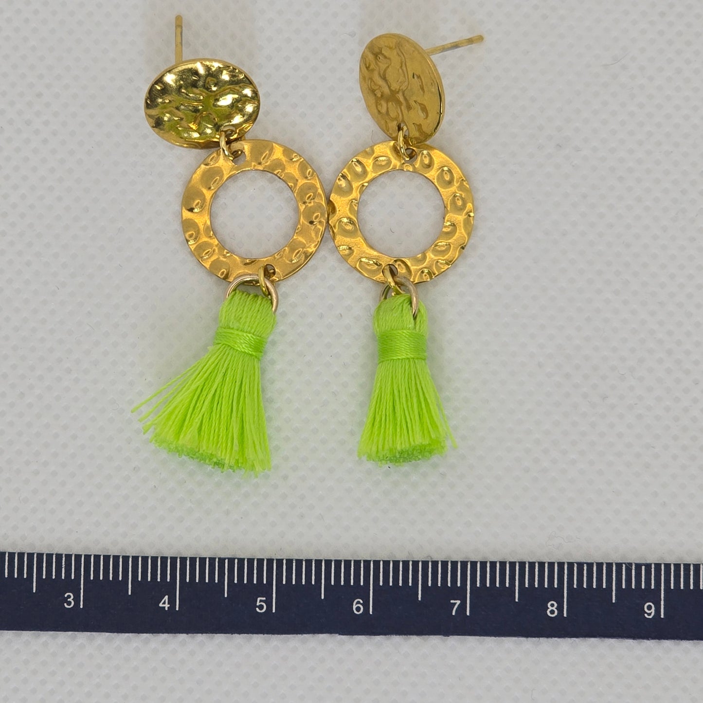 Earring- brass hammered effect circle with a lime green tassel, hanging from a brass hammered look post cover.