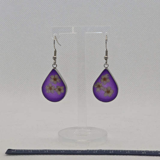 Earrings: silver-look teardrop shaped open bezel earrings with three white Alyssum flowers, set on a bed of translucent deep purple acrylic resin.